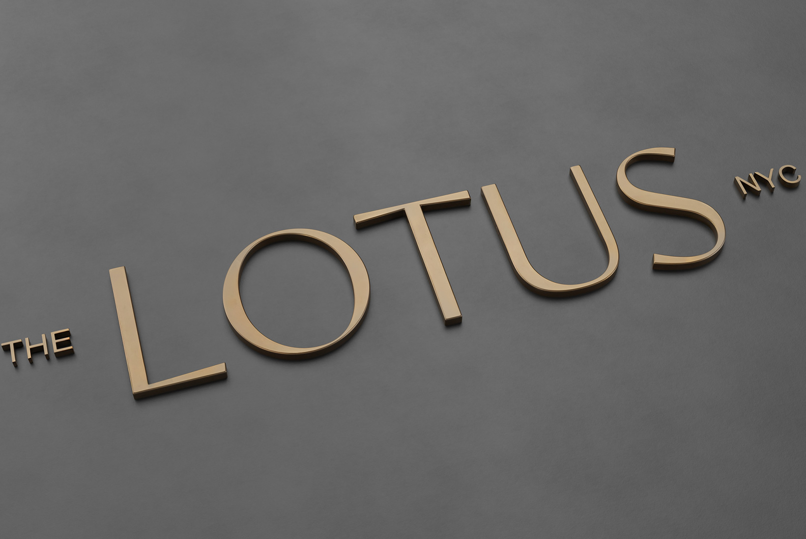 The Lotus NYC logo shown as brass raised letters